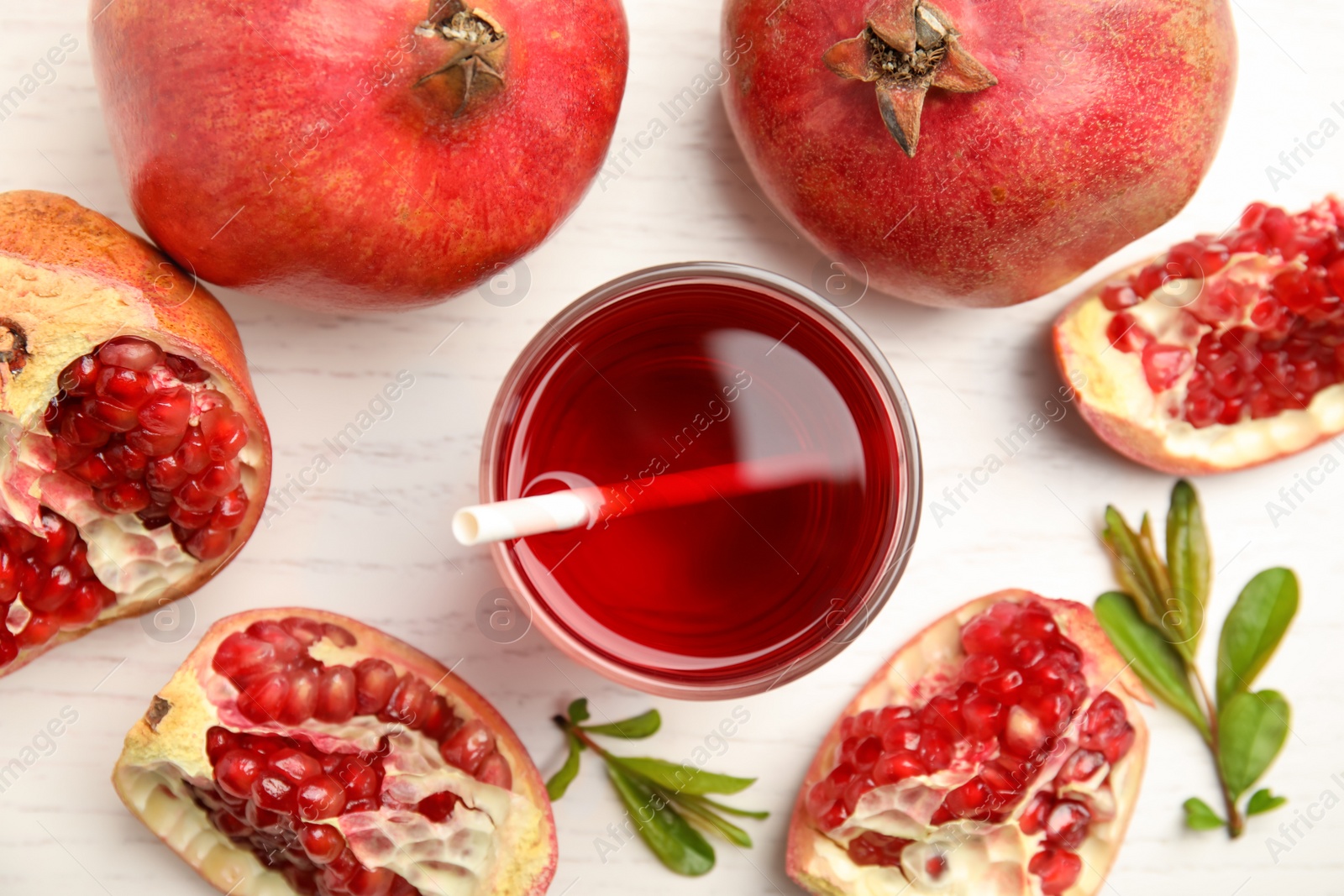 Photo of Glass of pomegranate juice and fresh fruits on white wooden table, flat lay