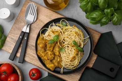 Photo of Delicious pasta and chicken with curry sauce served on grey table, flat lay