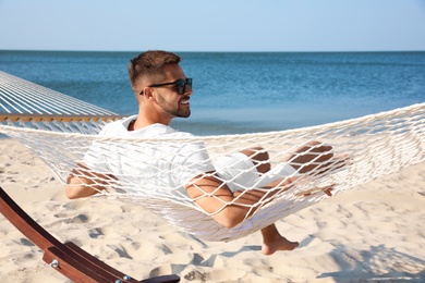 Photo of Young man relaxing in hammock on beach