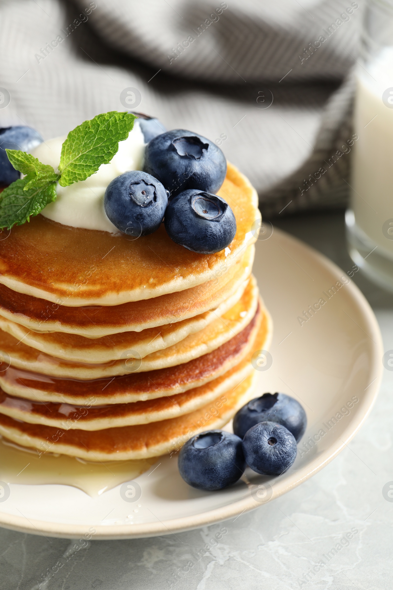 Photo of Plate of tasty pancakes with blueberries, sauce and mint on table, closeup