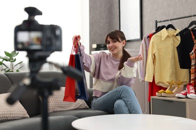 Smiling fashion blogger with shopping bags recording video at home