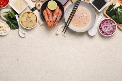 Photo of Cooking delicious ramen soup. Different ingredients on beige table, flat lay. Space for text