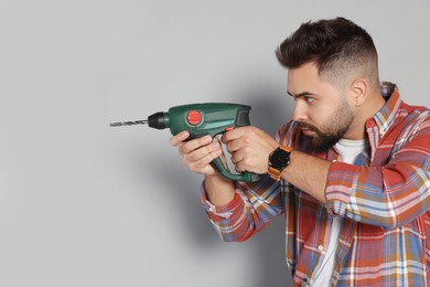 Photo of Young man with power drill on grey background