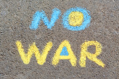 Photo of Words No War written with blue and yellow chalks on asphalt outdoors, top view