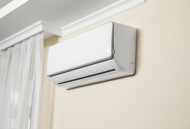 Photo of Modern air conditioner on white wall indoors