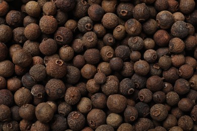 Aromatic allspice pepper grains as background, top view