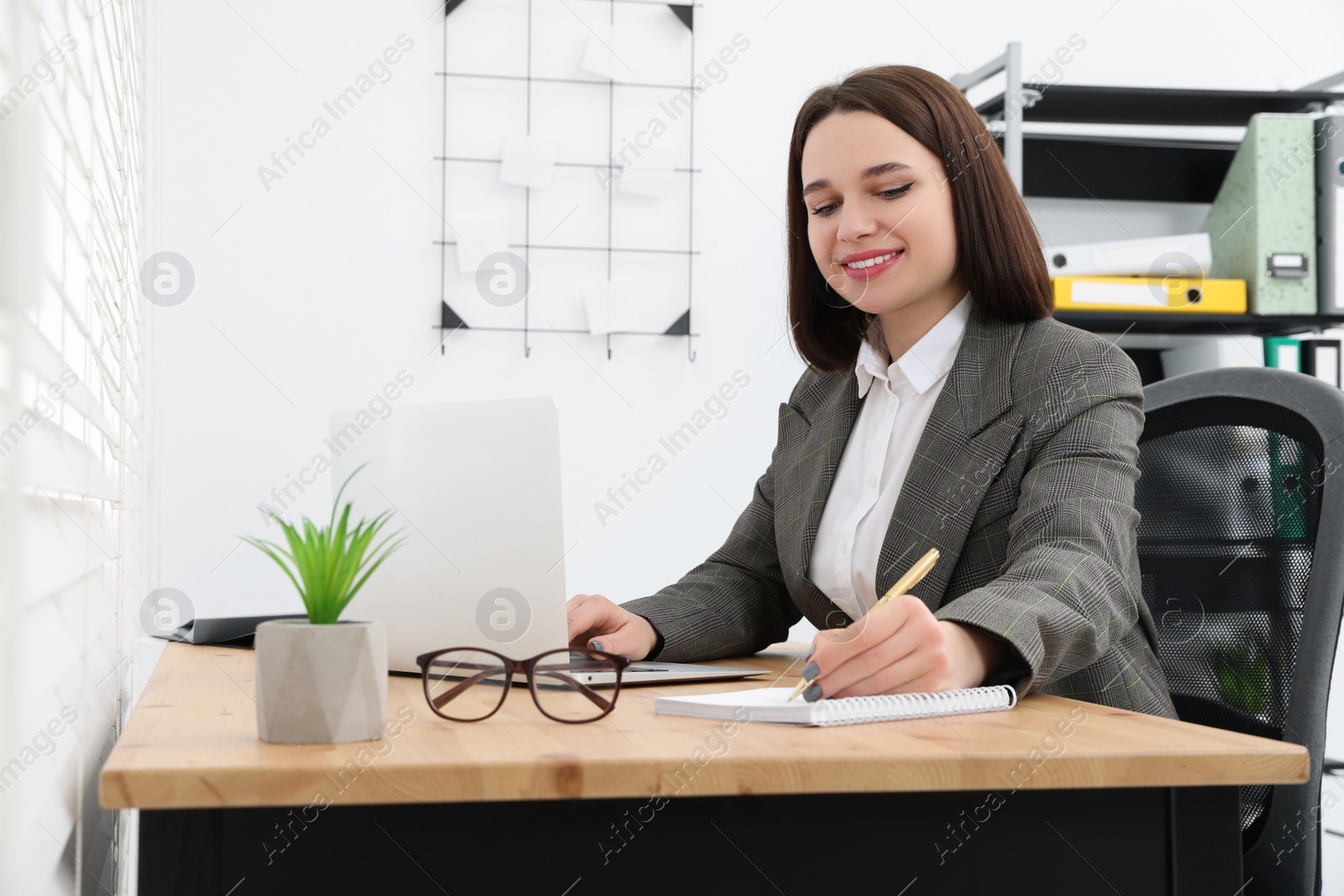 Photo of Happy young intern working at table in modern office