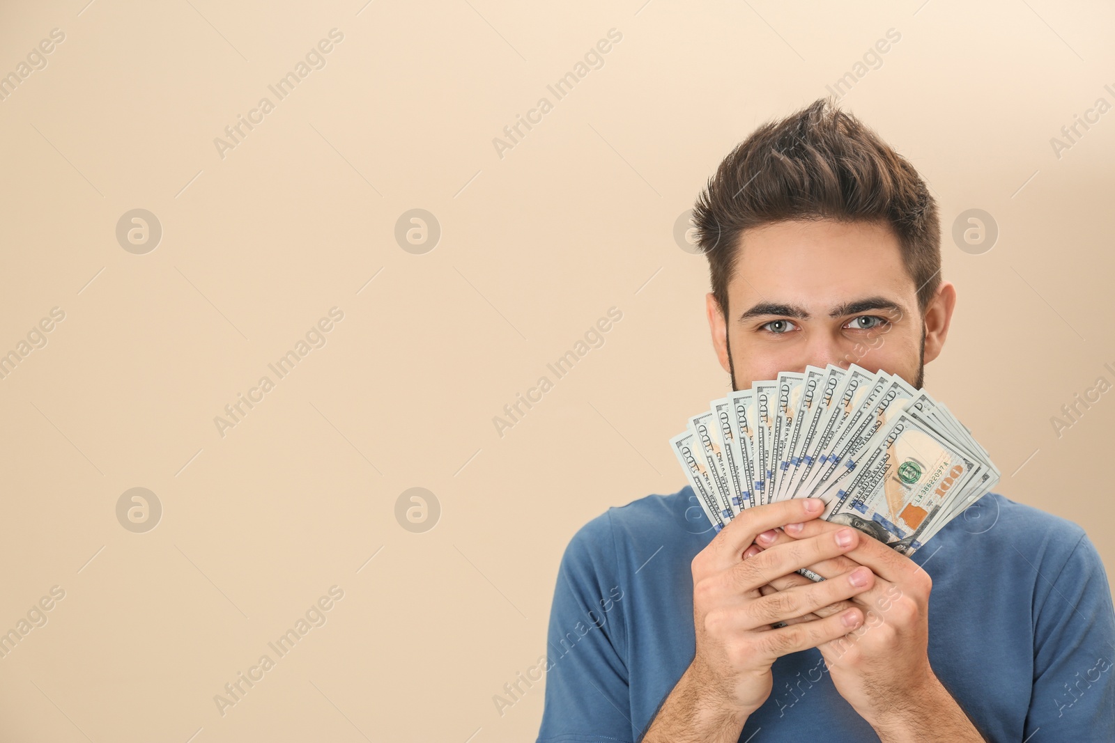 Photo of Happy young man with money on color background. Space for text