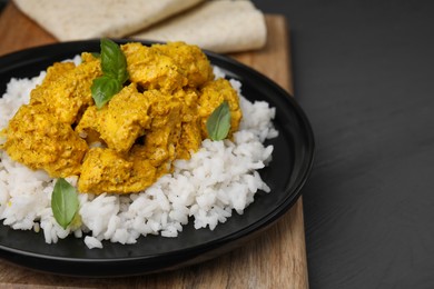 Photo of Delicious rice and chicken with curry sauce on grey wooden table, closeup. Space for text