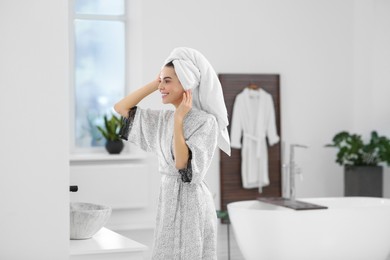 Photo of Beautiful happy woman wearing stylish bathrobe in bathroom