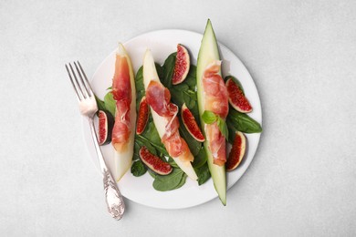 Photo of Tasty melon, jamon and figs on light grey table, top view