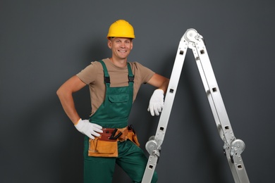 Professional constructor near ladder on black background