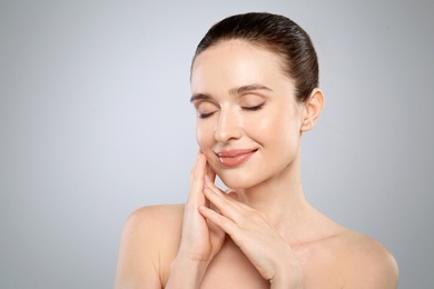 Portrait of beautiful young woman with perfect skin on grey background. Spa treatment