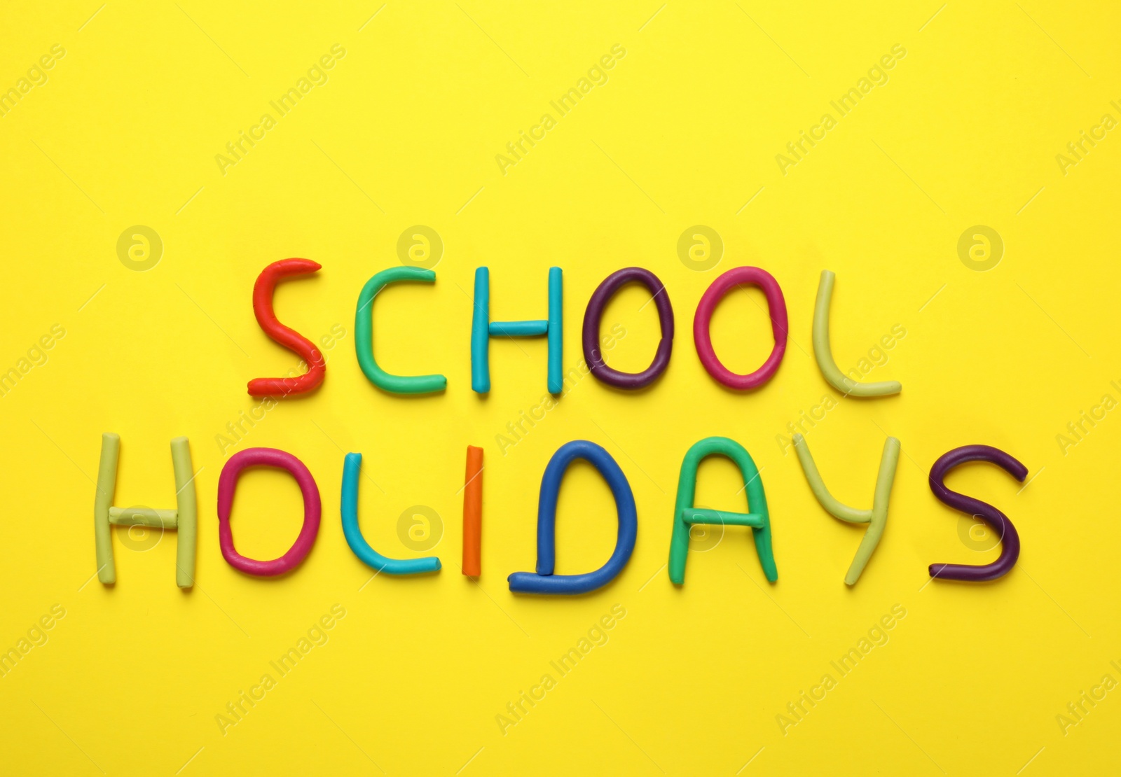Photo of Phrase School Holidays made of modeling clay on yellow background, top view