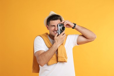 Male tourist taking picture on yellow background