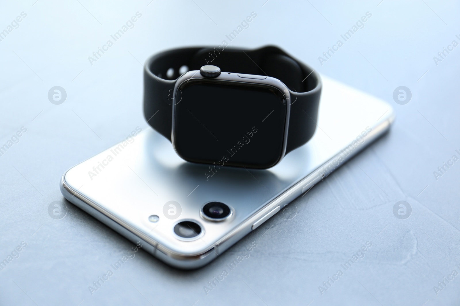 Stylish smart watch and phone on grey stone table, closeup Photo of Stylish smart watch and phone on grey stone table, closeup