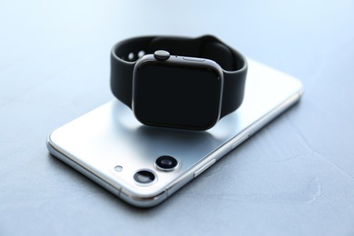 Photo of Stylish smart watch and phone on grey stone table, closeup