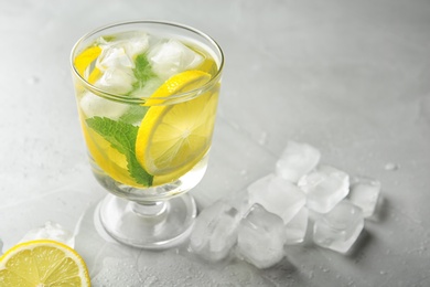 Glass with lemon water and ice cubes on table