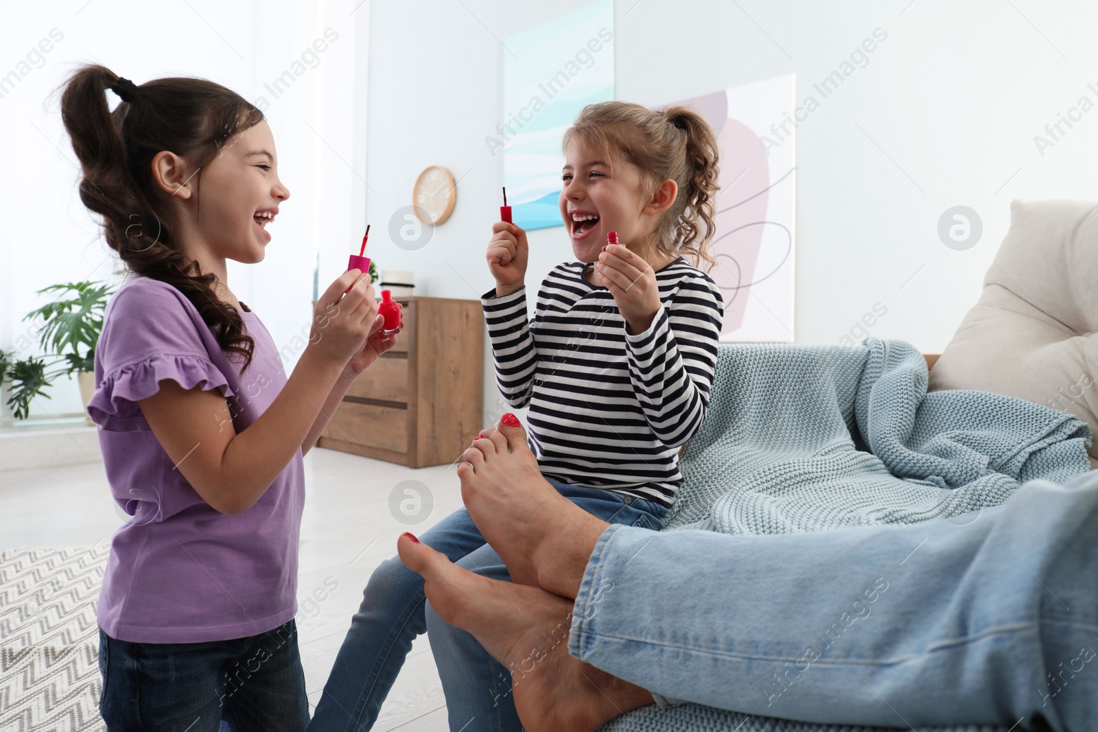 Photo of Cute little children applying polish on father's nails while he sleeping at home, closeup