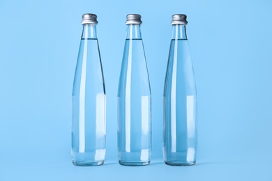Photo of Glass bottles with water on light blue background