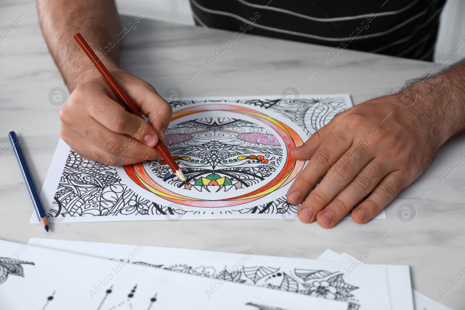 Photo of Man coloring antistress picture at table indoors, closeup