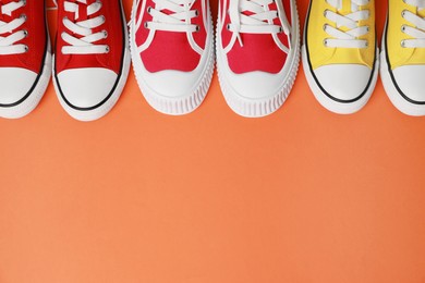 Photo of Different classic old school sneakers on orange background, above view. Space for text