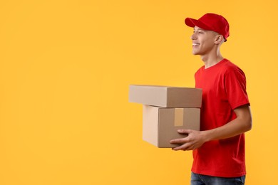 Happy courier with parcels on yellow background. Space for text