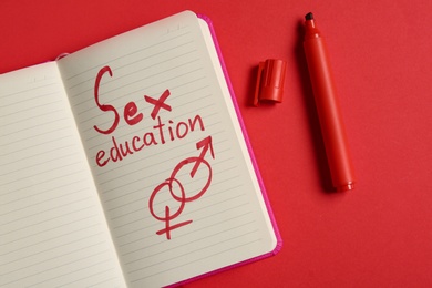 Notebook with phrase "SEX EDUCATION" on red background, flat lay
