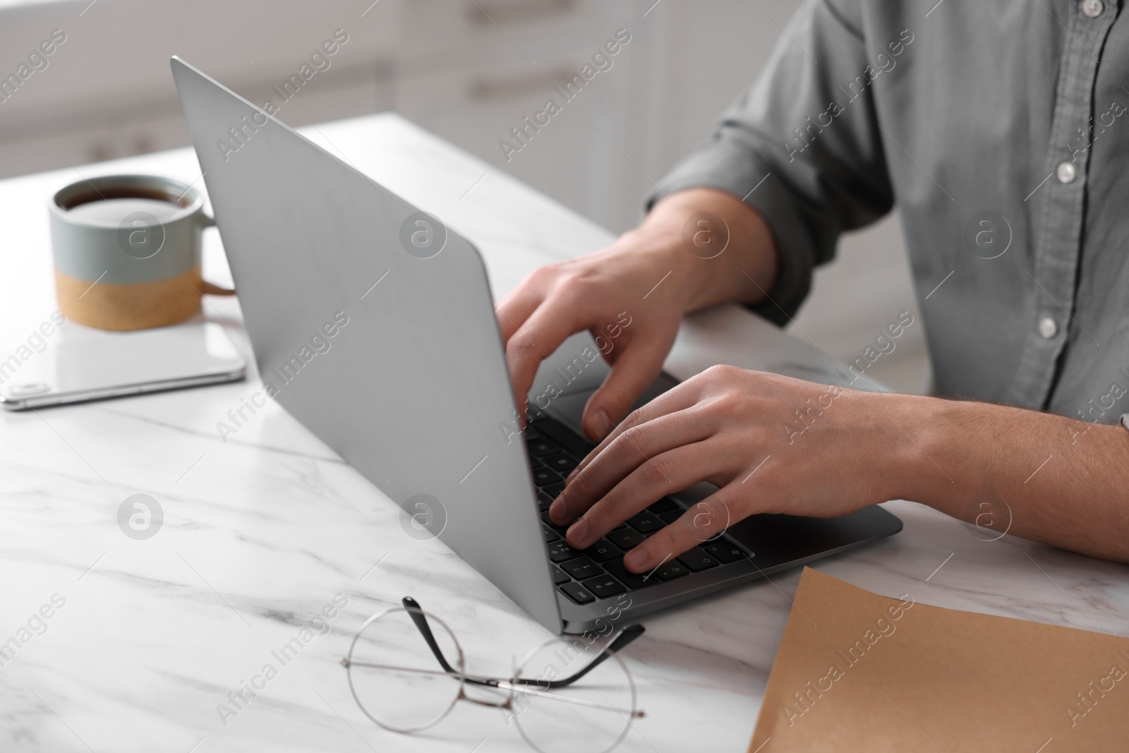 Photo of Man working on laptop at white marble table indoors, closeup