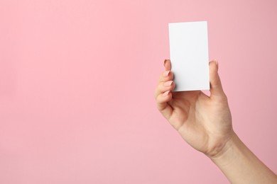 Woman holding blank business card on pink background, closeup. Mockup for design