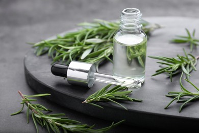 Photo of Bottle of rosemary essential oil on black table, closeup