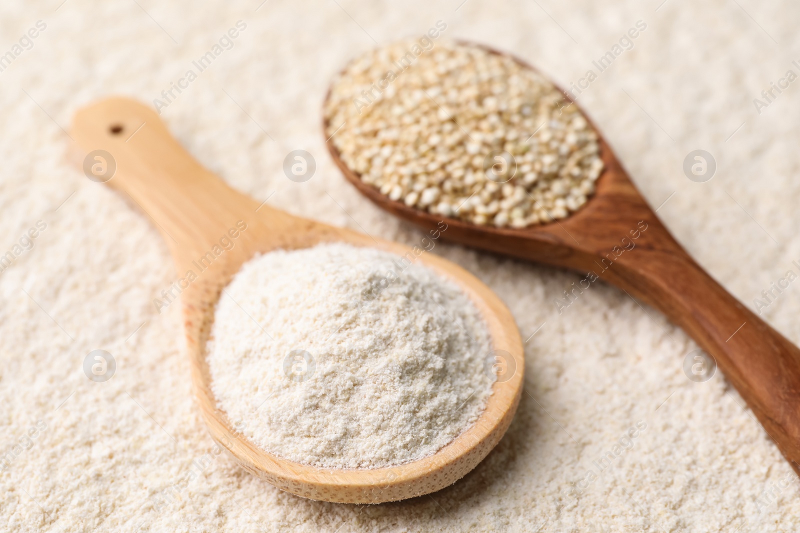 Photo of Wooden spoons with quinoa flour and seeds, closeup