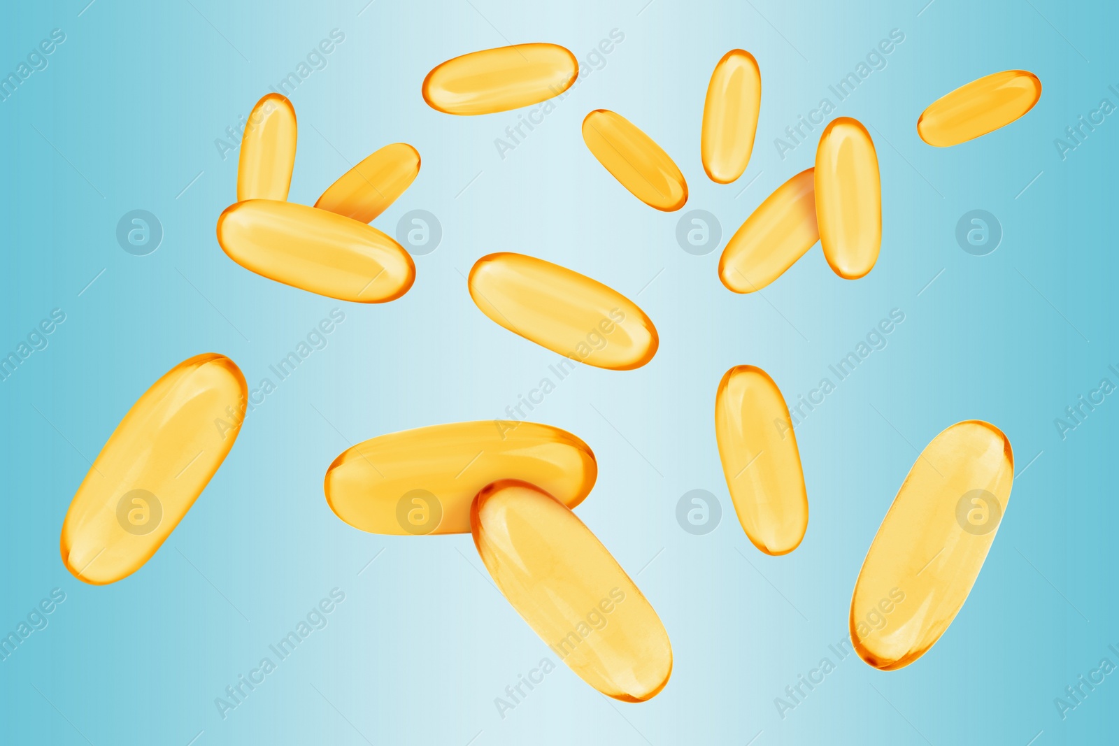 Image of Vitamin. Softgel capsules falling on light blue gradient background