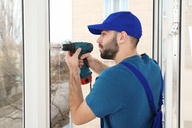 Construction worker using drill while installing window indoors