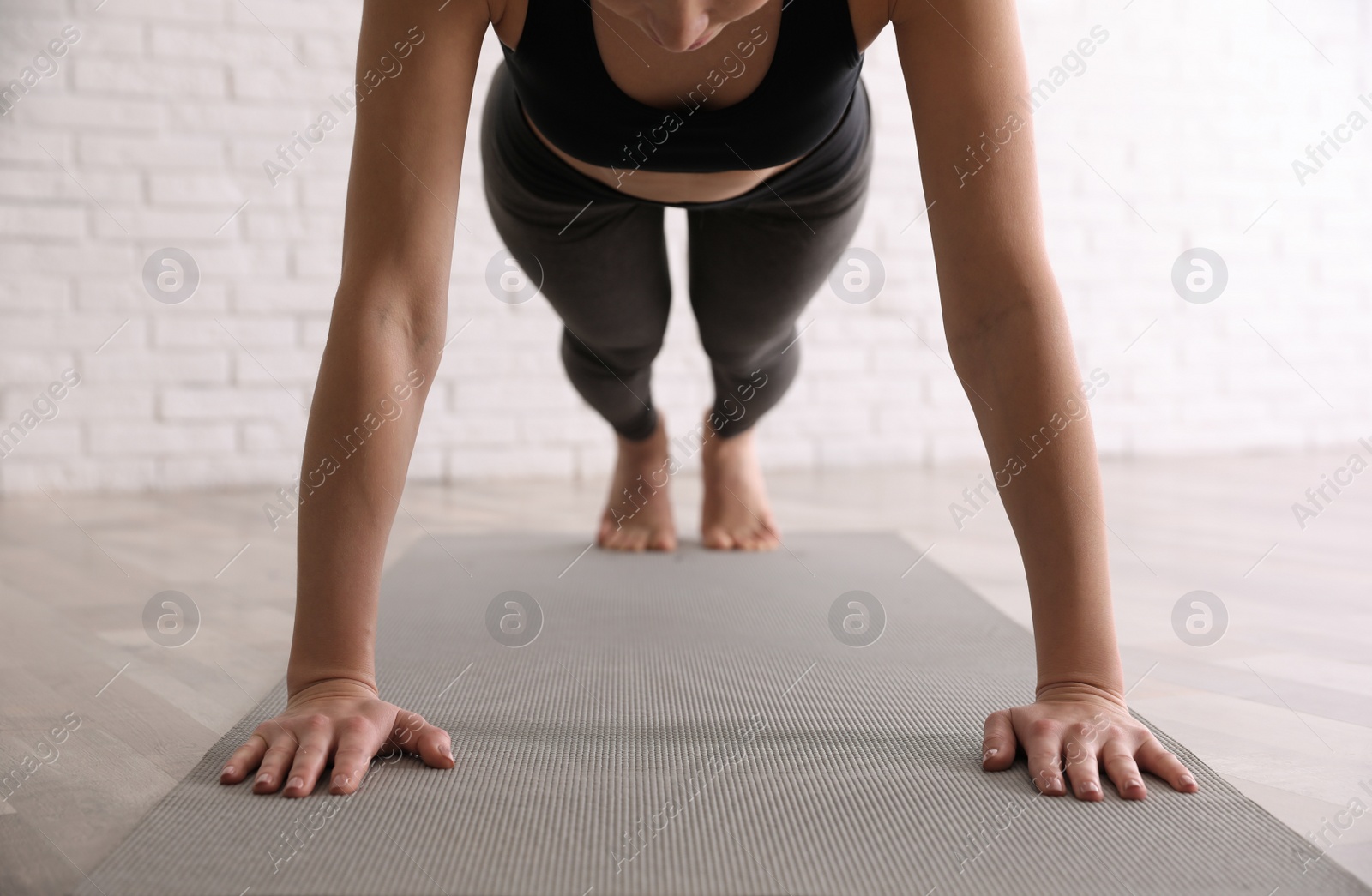 Photo of Young woman practicing plank asana in yoga studio, closeup. Phalankasana pose