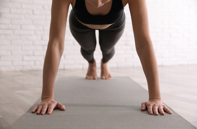 Photo of Young woman practicing plank asana in yoga studio, closeup. Phalankasana pose