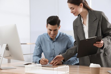 Businesswoman helping intern with work in office