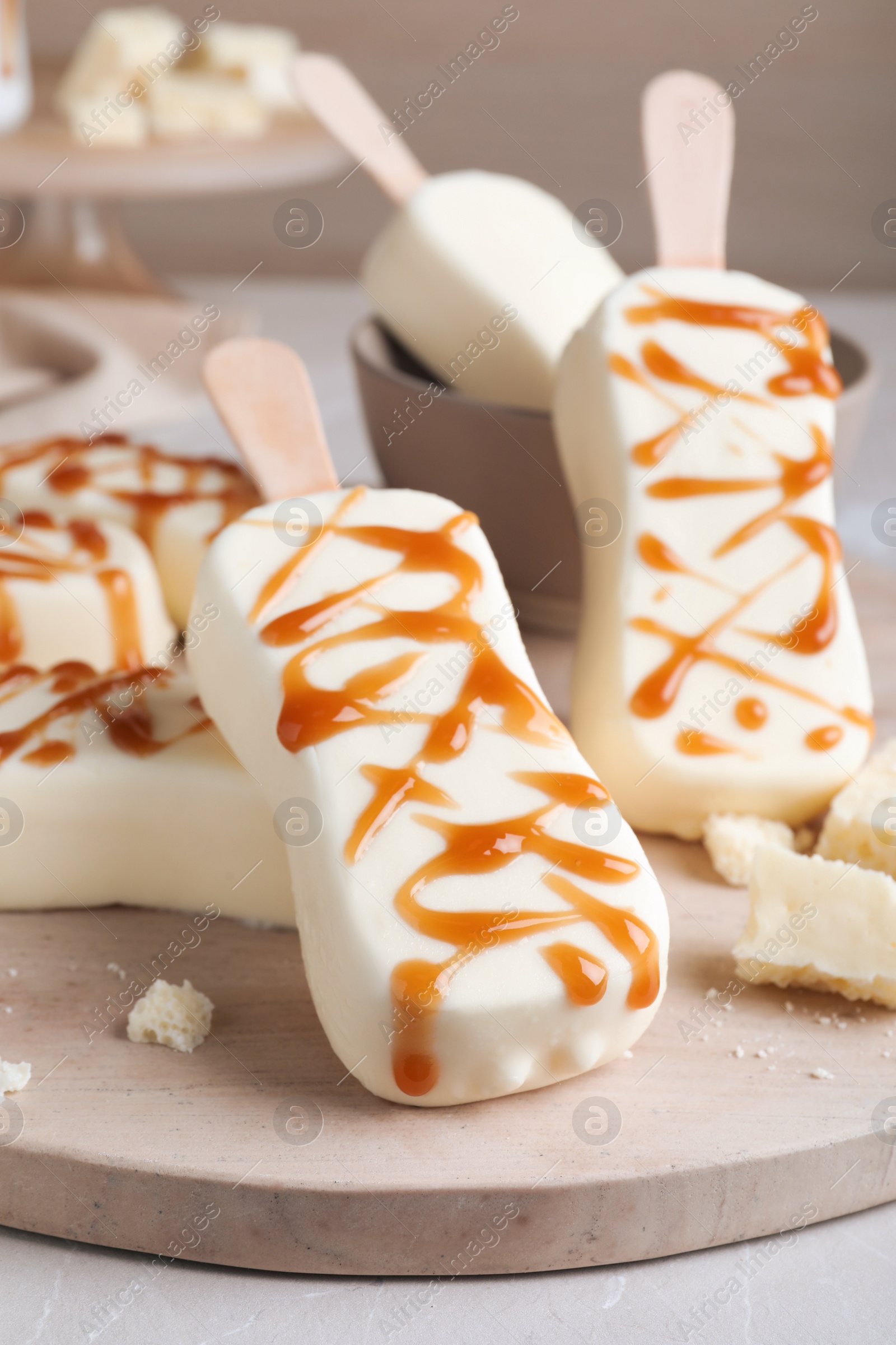 Photo of Delicious glazed ice cream bars and chocolate on board, closeup