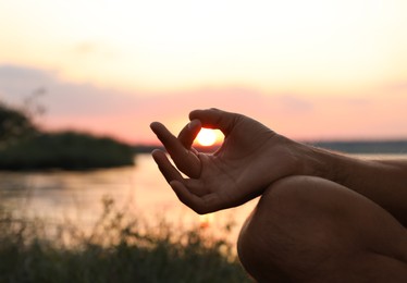 Photo of Man meditating near river at sunset, closeup. Space for text
