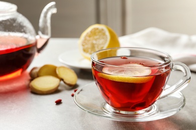 Photo of Glass cup of healthy goji tea with lemon on grey table. Space for text