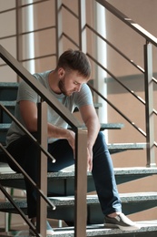 Photo of Depressed young man sitting on stairs