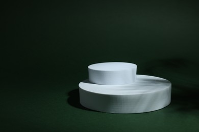 Photo of Product photography props. Round shaped podiums on green background, space for text