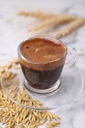 Photo of Cup of barley coffee and grains on light table, closeup