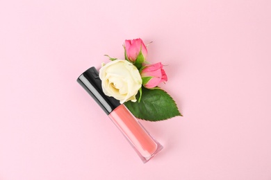 Photo of Lip gloss and flowers on color background