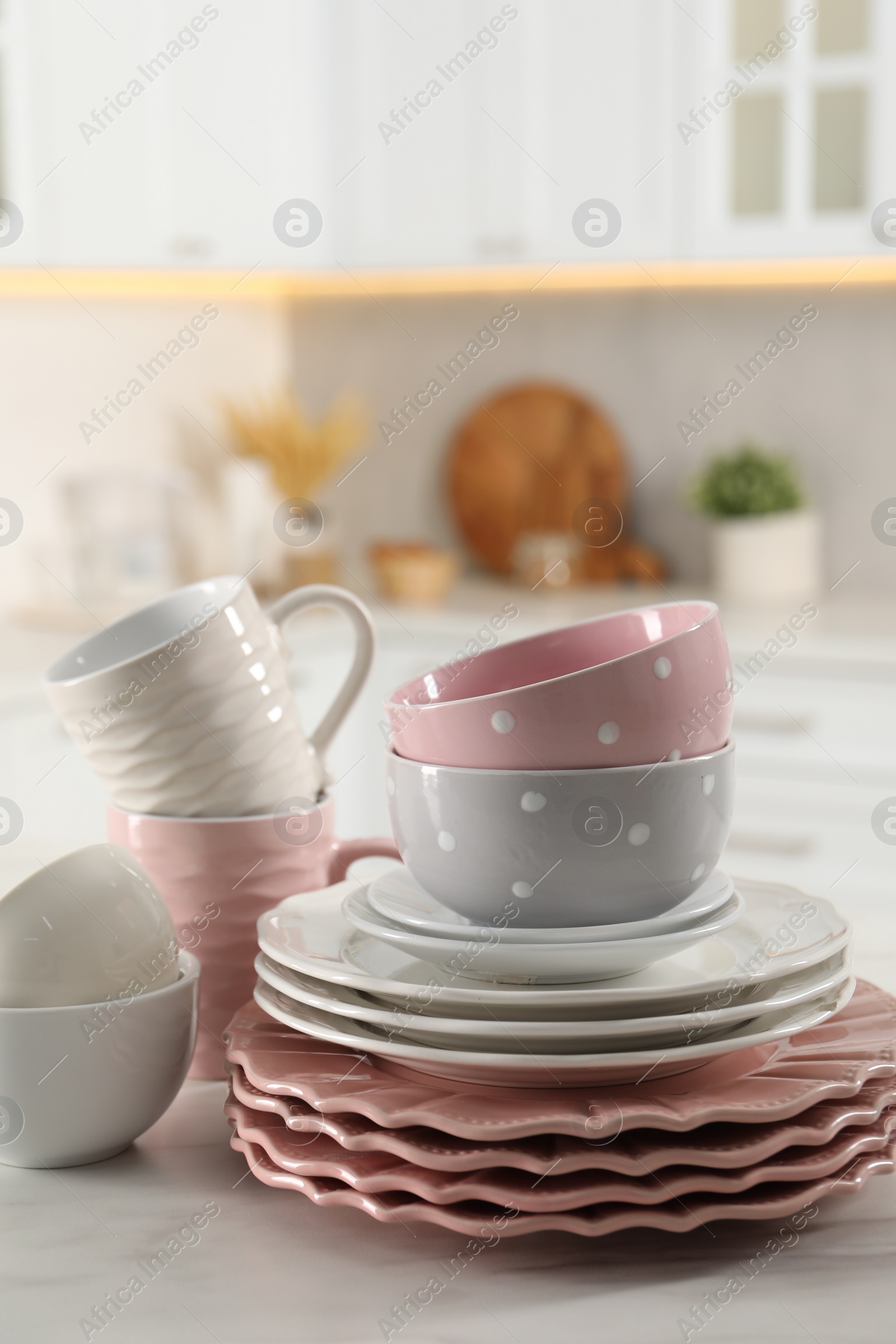 Photo of Many different clean dishware and cups on white marble table in kitchen