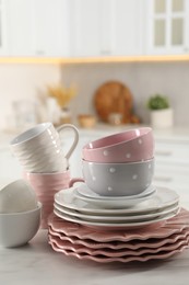 Many different clean dishware and cups on white marble table in kitchen