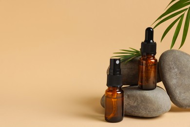 Photo of Bottles of organic cosmetic products, green leaf and stones on beige background, space for text