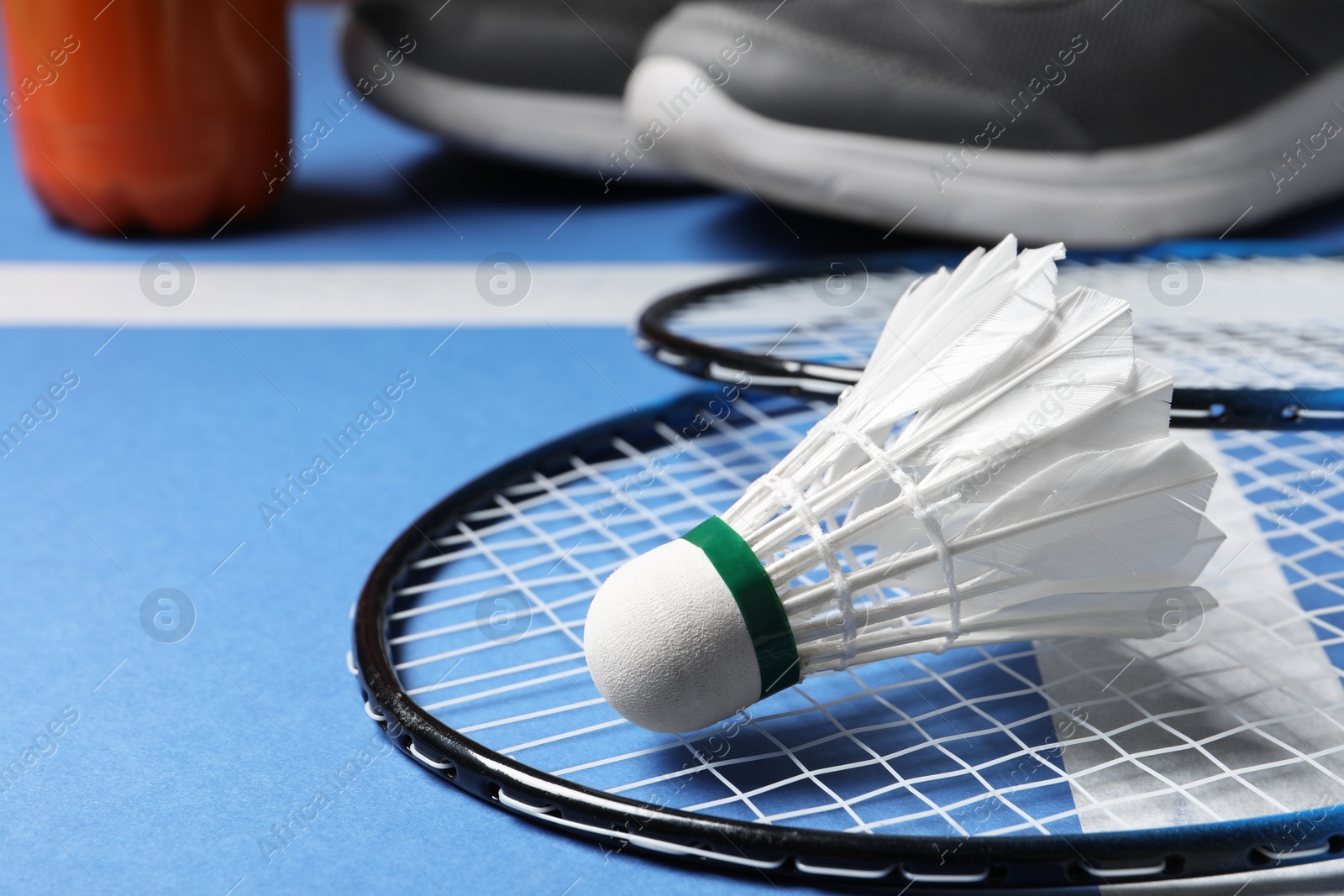 Photo of Feather badminton shuttlecock and rackets on court, closeup