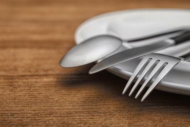 Photo of Empty dishware and cutlery on wooden table, close up view. Table setting