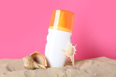 Suntan product, seashell and starfish on sand against pink background